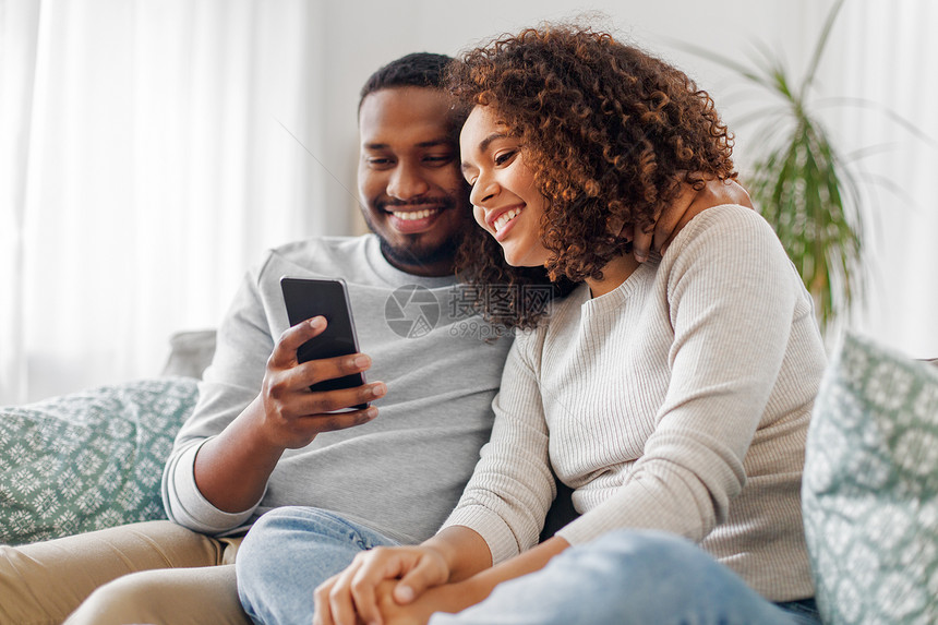 技术,互联网人的快乐的非裔美国人夫妇与智能手机家里非裔美国人夫妇家里有智能手机图片