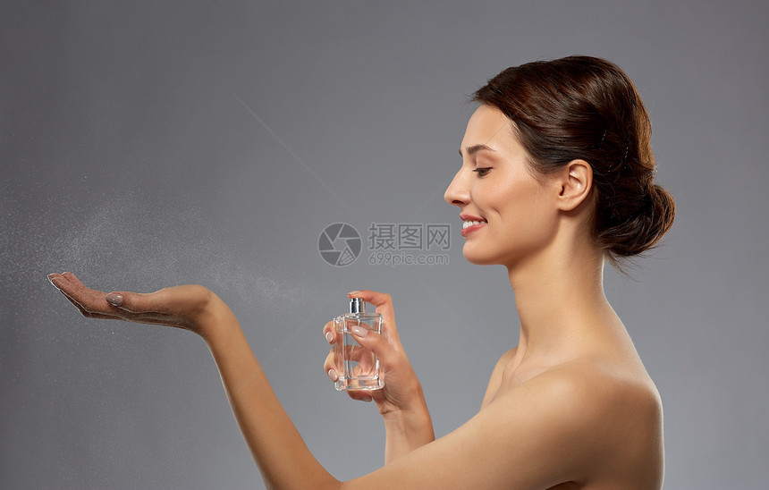 香水,美丽奢侈的快乐的微笑年轻妇女与香水灰色背景带香水的快乐女人图片