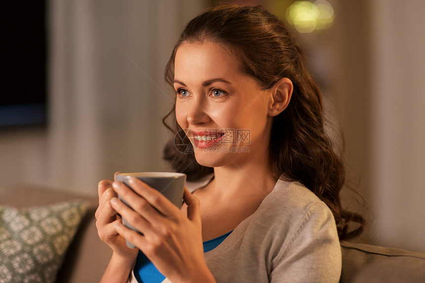 人,饮料休闲快乐的女人家里喝杯茶或咖啡晚上快乐的女人家喝茶或咖啡图片