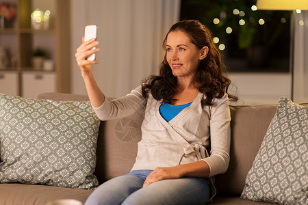人,技术休闲快乐的女人晚上家用智能手机自拍快乐的女人家里用智能手机自拍图片