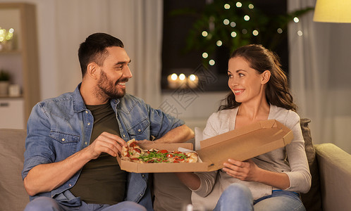 休闲,人快餐的快乐的夫妇家里吃外卖比萨饼晚上快乐的夫妇家吃外卖披萨图片