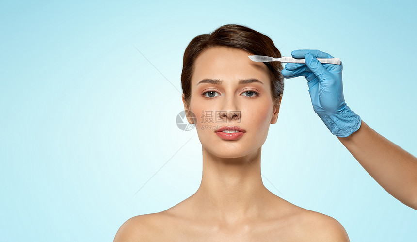 整形手术美容美丽的年轻女人手与手术刀蓝色背景漂亮的年轻女人手手术刀图片
