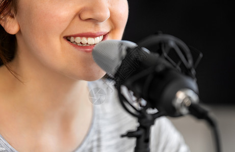 录音功能技术,大众媒体人的密切妇女与麦克风交谈录音播客演播室靠近女人麦克风说话背景