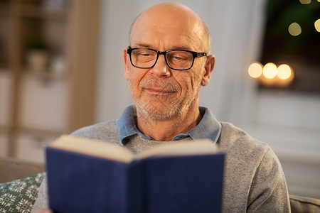 老年休闲人的快乐的秃顶老人晚上坐沙发上看书快乐的秃顶老人沙发上看书家图片