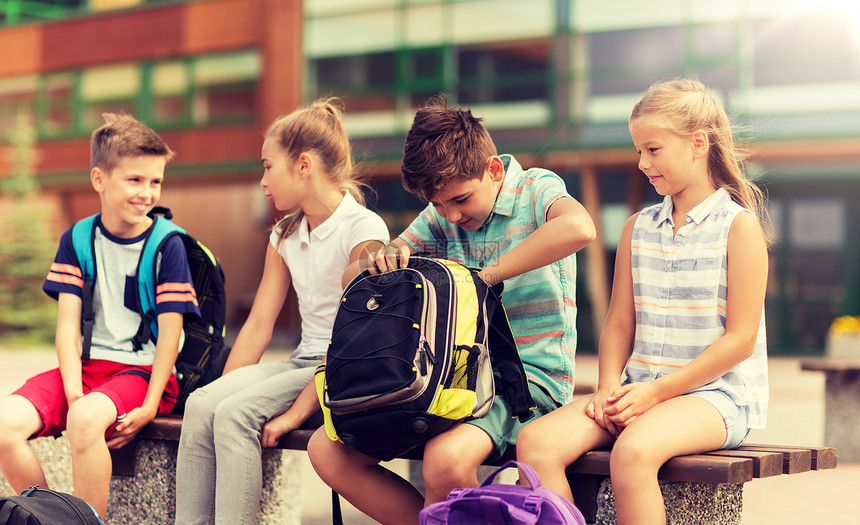 小学教育,友谊,童年,沟通人的群快乐的小学生,背包坐户外长凳上群带背包的小学生图片