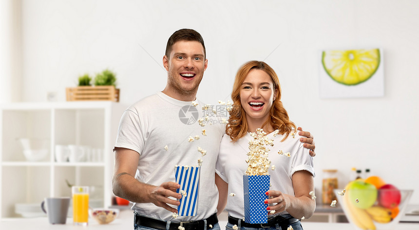 食物,娱乐人们的幸福的夫妇穿着白色T恤吃爆米花家庭厨房背景穿着白色T恤吃爆米花的幸福夫妇图片