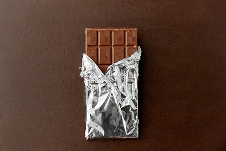 糖果,糖果食品牛奶巧克力棒箔包装棕色背景棕色背景上箔纸包装的巧克力棒图片