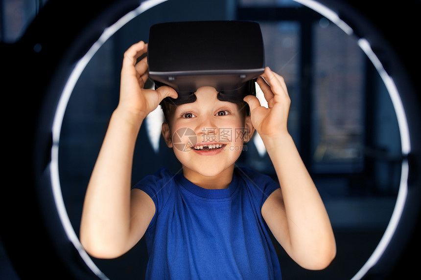 未来的技术人们的快乐的微笑男孩VR眼镜或虚拟现实耳机白色照明黑暗的房间男孩戴着VR眼镜,黑暗的房间里照明图片