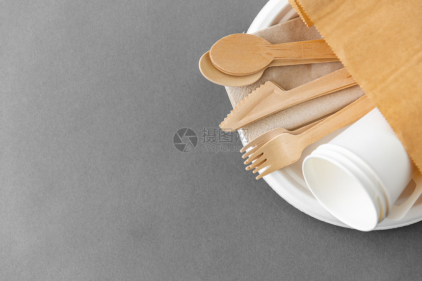 餐具,回收生态友好的套木制勺子,叉子刀子与纸杯盘子上的灰色背景纸盘上的木制勺子叉子刀子图片