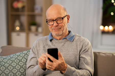 技术,人沟通的快乐的微笑秃顶老人家里的智能手机短信快乐的老人家用智能手机发短信背景图片