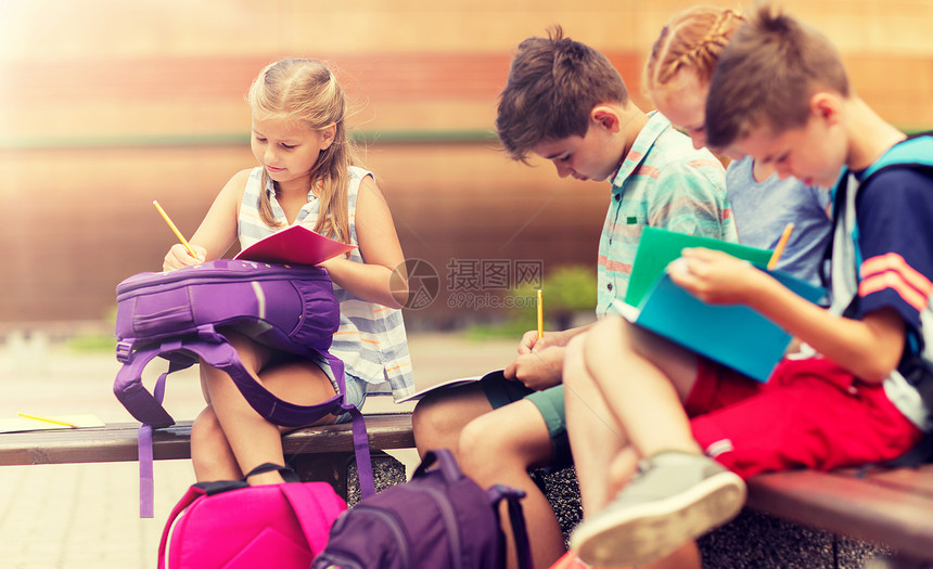 小学教育,友谊,童年,沟通人的群快乐的小学生,背包笔记本坐长凳上,户外做作业群快乐的小学生户外图片