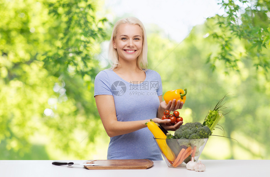 健康的饮食,烹饪,食物,饮食人们的快乐的微笑年轻妇女与碗蔬菜超过绿色的自然背景微笑的年轻女人煮蔬菜图片