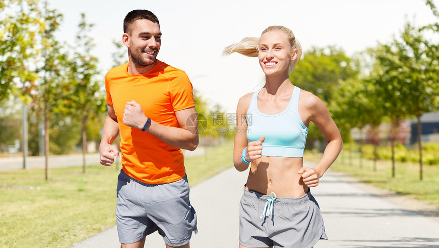 运动,健康的生活方式人们的微笑夫妇与健身跟踪者沿着道路城市街道背景快乐的夫妇与健身跟踪器户外运行图片