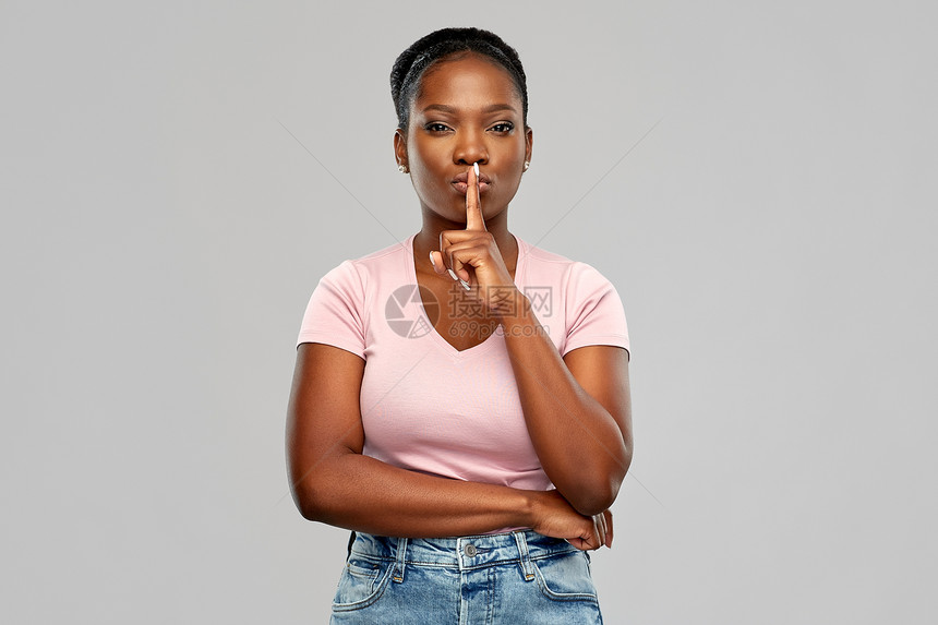 人,沉默秘密的非洲裔美国年轻妇女,手指嘴唇上灰色的背景非裔美国妇女,手指嘴唇上图片