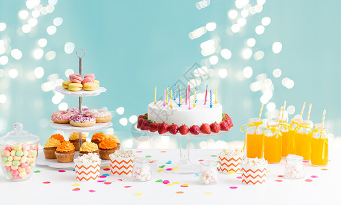 生日蛋糕卡派节日生日蛋糕与蜡烛草莓,饮料食物桌子上的灯光蓝色背景生日聚会上桌子上的食物饮料背景