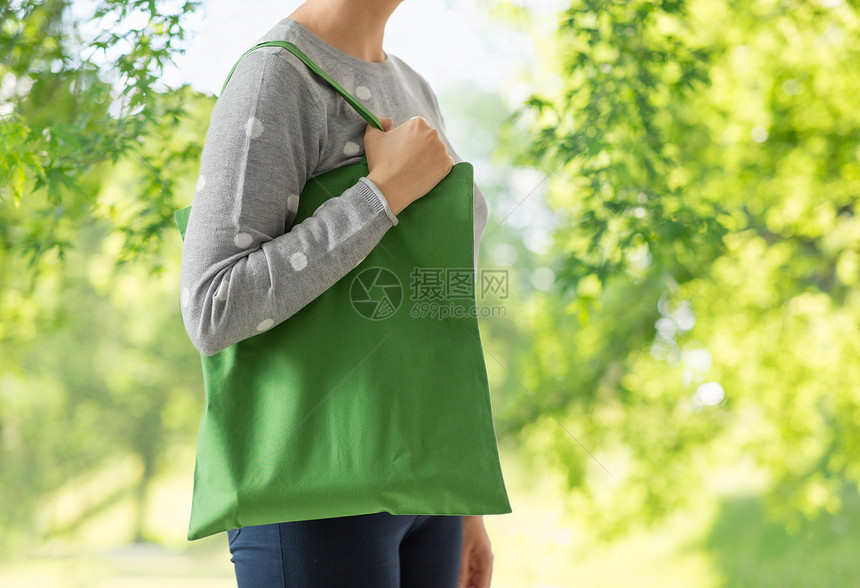 消费主义,可持续生态友好的女与绿色可重复用的帆布袋,用于自然背景下的食品购物妇女与可重复用的帆布袋食品购物图片