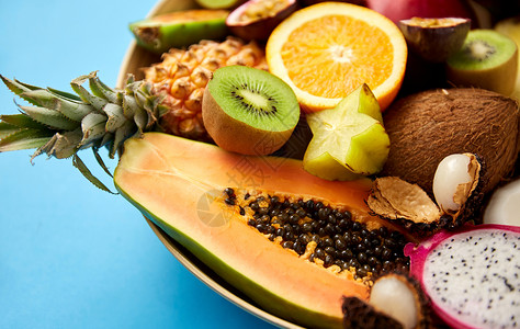 食物,夏天健康的饮食蓝色背景上同异国水果的盘子蓝色背景上的异国水果盘子图片