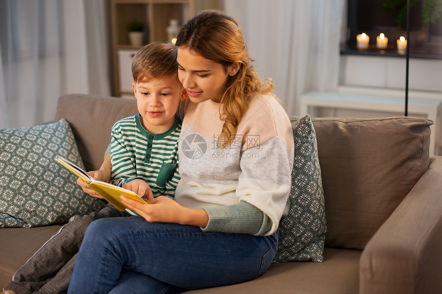 家庭休闲人的快乐微笑的母亲小儿子坐家里的沙发上看书快乐的母子家看书沙发图片