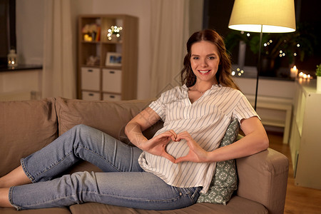 怀孕人们的快乐的微笑孕妇沙发上手心手势家里快乐的孕妇表现出手心的手势图片