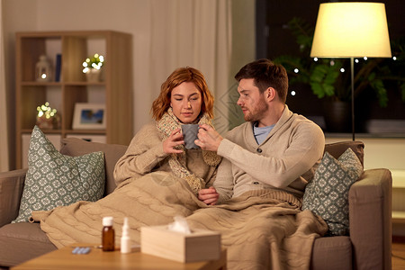 健康,流感人们的生病的年轻夫妇戴着围巾家喝热茶生病的年轻夫妇家喝热茶图片