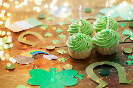 圣帕特里克日,假日庆祝绿色纸杯蛋糕与蜡烛其他派道具木制桌子上的节日灯绿色纸杯蛋糕圣帕特里克日派道具背景图片
