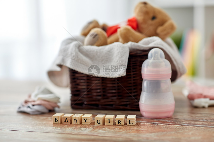 婴儿期服装泰迪熊柳条篮子与婴儿的东西玩具块木制桌子家里泰迪熊玩具篮子里,婴儿的东西桌子上图片
