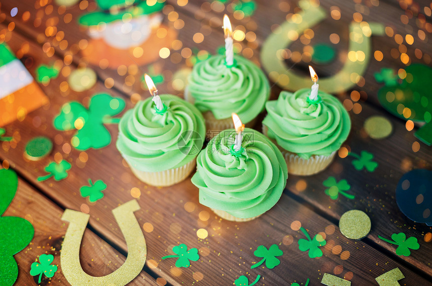 圣帕特里克日,假日庆祝绿色纸杯蛋糕与蜡烛其他派道具木制桌子上的节日灯绿色纸杯蛋糕圣帕特里克日派道具图片