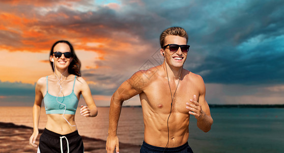 健身,运动技术快乐的夫妇与耳机运行海上日落天空的背景夫妇带着耳机海上跑图片