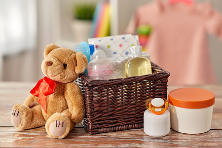 婴儿期护理产品的婴儿的东西柳条篮子泰迪熊玩具木制桌子家里篮子里的婴儿用品桌子上的泰迪熊玩具背景图片