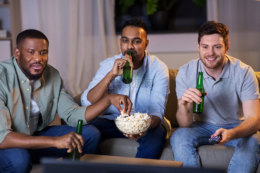 友谊休闲人的快乐的男朋友,晚上家喝啤酒爆米花看电视快乐的男朋友家里喝啤酒看电视图片