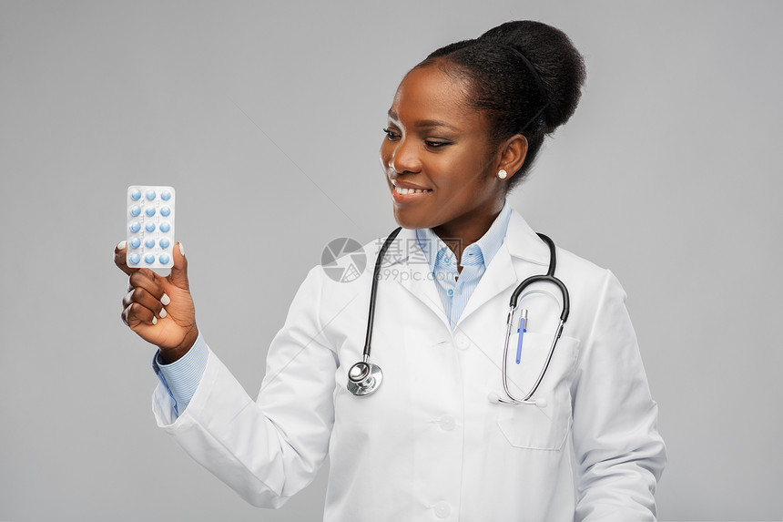 医学,职业医疗保健快乐微笑的非裔美国女医生或穿着白色外套,背景上有药丸听诊器非裔美国女医生带药丸图片