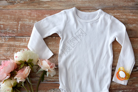 婴儿服装,婴儿期服装白色紧身衣与肥皂花木桌上婴儿紧身衣与肥皂花木头上图片