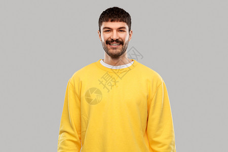人们的微笑的年轻人穿黄色运动衫灰色背景穿着黄色运动衫的微笑的年轻人图片
