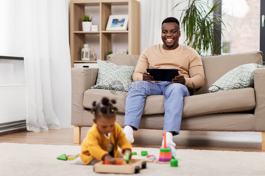 家庭,技术人的快乐的非裔美国人父亲与平板电脑电脑婴儿女儿玩玩具块家里快乐的父亲家里有平板电脑婴儿图片