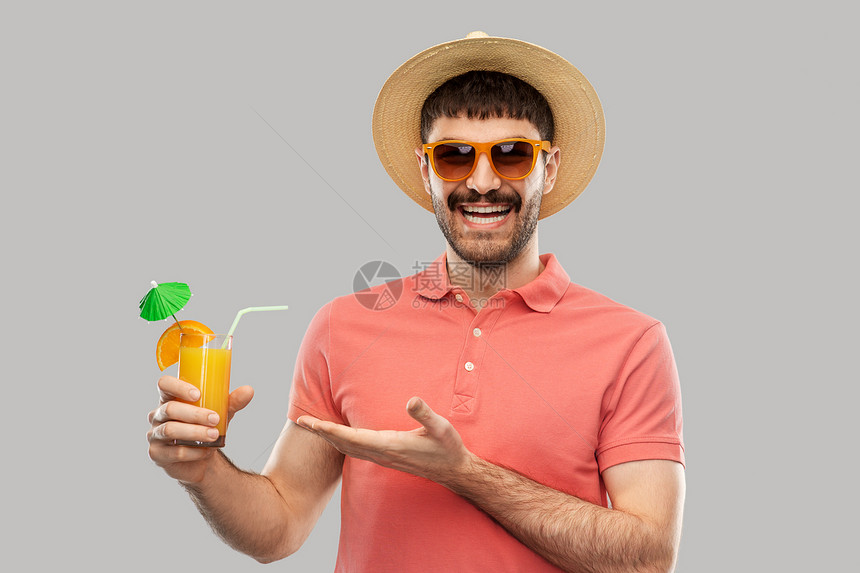 暑假,假期人们的快乐的微笑年轻人戴着太阳镜草帽,灰色背景下喝橙汁鸡尾酒戴着草帽橙汁鸡尾酒的快乐男人图片