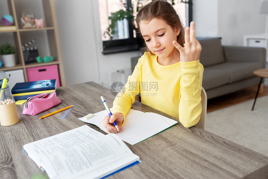 孩子,教育学的快乐的学生女孩,用书本数手指,家里写笔记本学生女孩带着书家里写笔记本图片