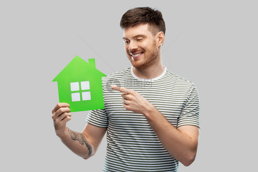 生态生活,环境可持续微笑的年轻人穿着条纹T恤,灰色背景上着绿色的房子图标微笑的年轻人着绿色的房子图标图片