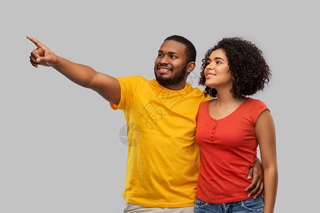 关系人的快乐的非裔美国人夫妇指着灰色背景的东西快乐的非裔美国人夫妇图片