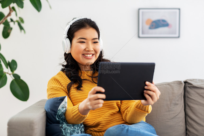 人与休闲的快乐微笑的亚洲年轻妇女耳机听音乐平板电脑电脑家里带耳机平板电脑的亚洲女人家图片