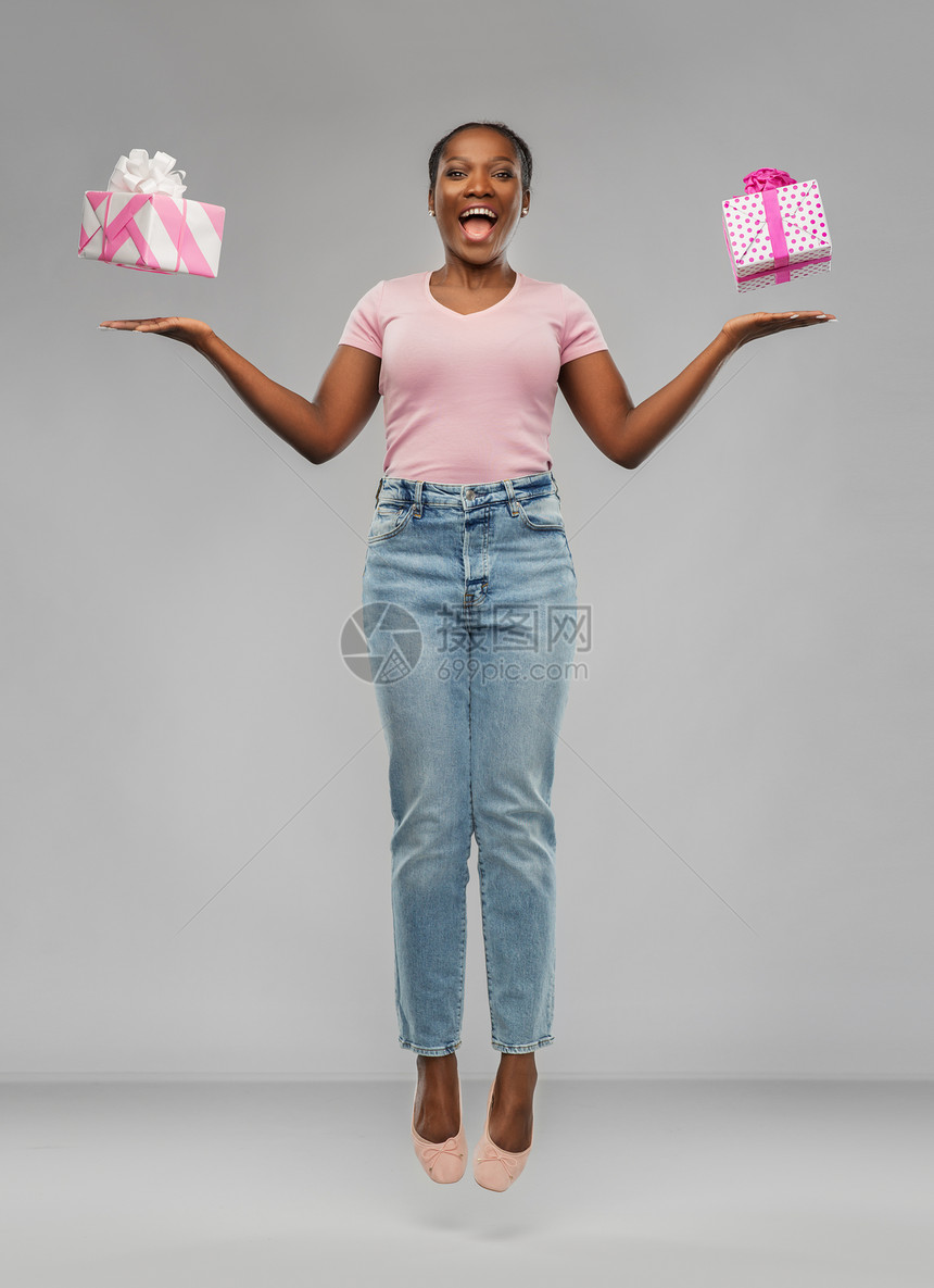 生日礼物惊喜快乐的非裔美国年轻妇女与礼品盒灰色背景快乐的非裔美国女人带着礼品盒图片