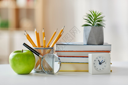 教育学校书籍,放大镜,铅笔,种植花盆与绿色苹果闹钟家里家里桌子上的书,苹果背景