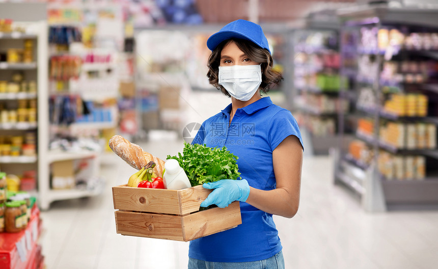 健康保护安全大流行分娩妇女戴着保护医疗面罩手套,超市或杂货店背景下着带食物的木箱送货女孩戴着面具,盒子里有图片