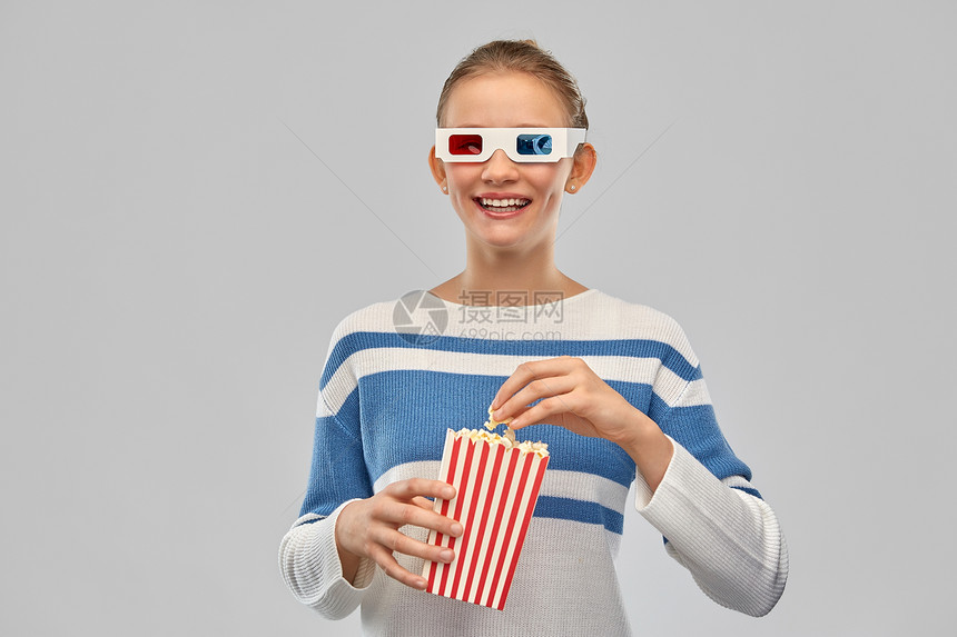 电影人们的快乐的微笑少女3D电影眼镜吃爆米花条纹桶灰色背景十几岁的女孩3D电影眼镜里吃爆米花图片