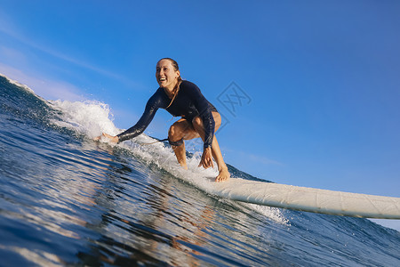 阳光明媚的日子里,女冲浪者蓝色的波浪上冲浪高清图片