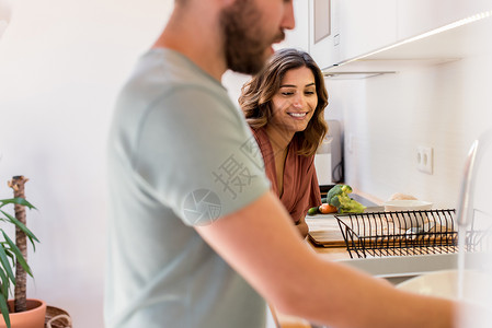 夫妇分担家务快乐的女人看着男人洗碗图片