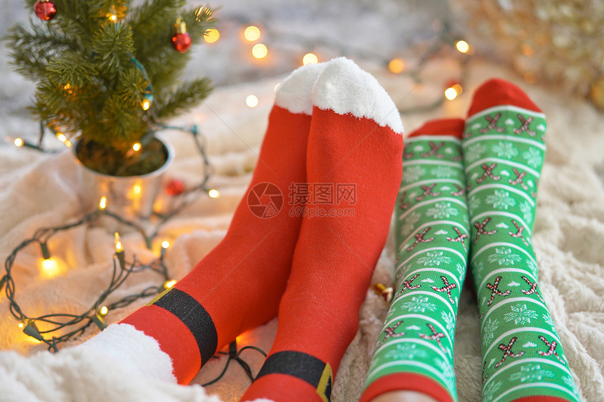 圣诞树附近穿着圣诞袜的脚夫妇坐毯子上,放松,用羊毛袜子热身他们的脚寒假圣诞节的图片