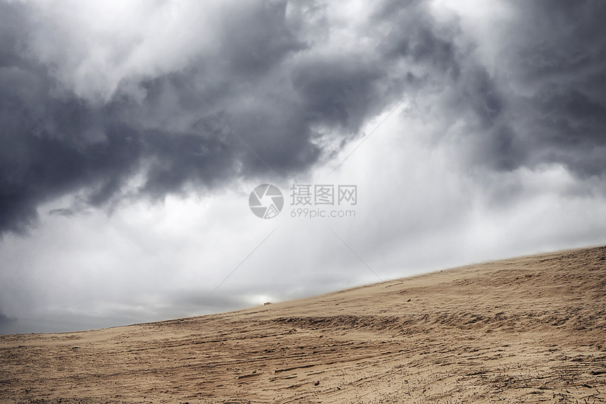 沙尘暴干燥的沙漠下,多云的天空下,乌云密布图片