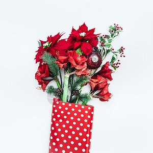 绿色圆点冬天的花束白色桌面上,红色圆点包装纸中有束花品红冷杉枝上面的风景圣诞鲜花安排背景