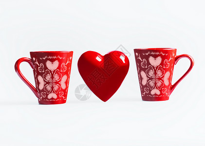 两个红色杯子,白色的背景上有心形装饰创造情人节或爱情图片