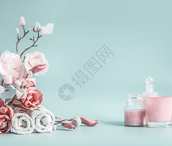 粉红色蜡烛美丽的背景与淡粉色的花化妆品淡蓝色的背景背景